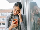 Une femme regarde son smartphone avec un air sérieux