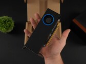 Une personne tenant le GPU de station de travail Intel Arc Pro B50 à profil bas avec un refroidisseur de type ventilateur, montré contre sa boîte d'emballage. (Source de l'image : ETA Prime via YouTube)