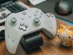 Manette de Xbox blanche posée sur un bureau en bois à côté d'une petite figurine de chat (Image source : FOX ^.ᆽ.^= ∫ via Pexels)