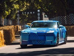 La Jaguar Type 01 EV, dans sa livrée « Blue Exuberant Modernism Camouflage », file à toute allure devant la grille de départ de la course de côte de Goodwood